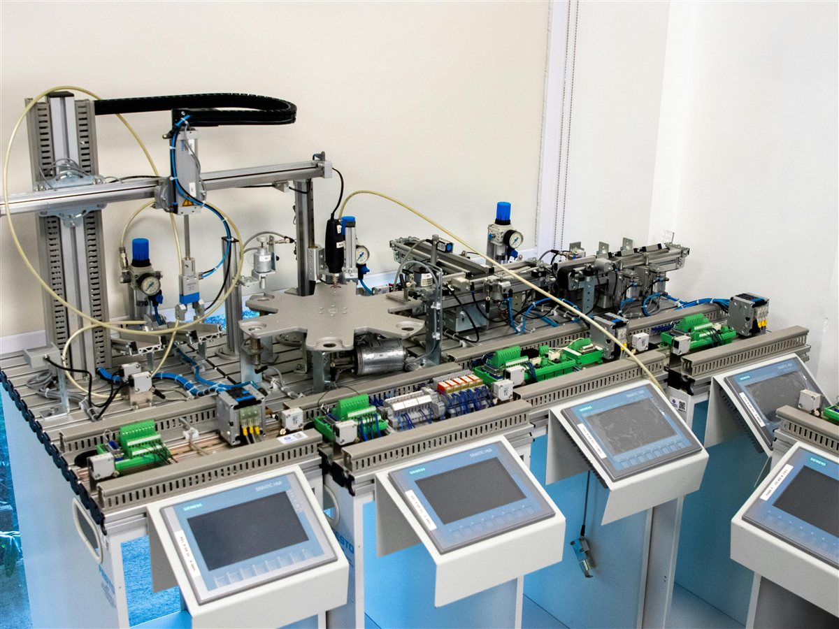 Technician troubleshooting Allen-Bradley PLC with ladder logic on laptop